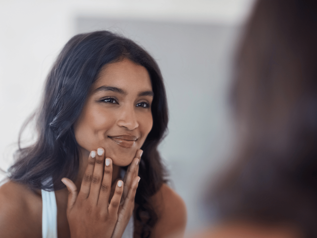 beautiful woman smiling in the mirror gently touching her face.